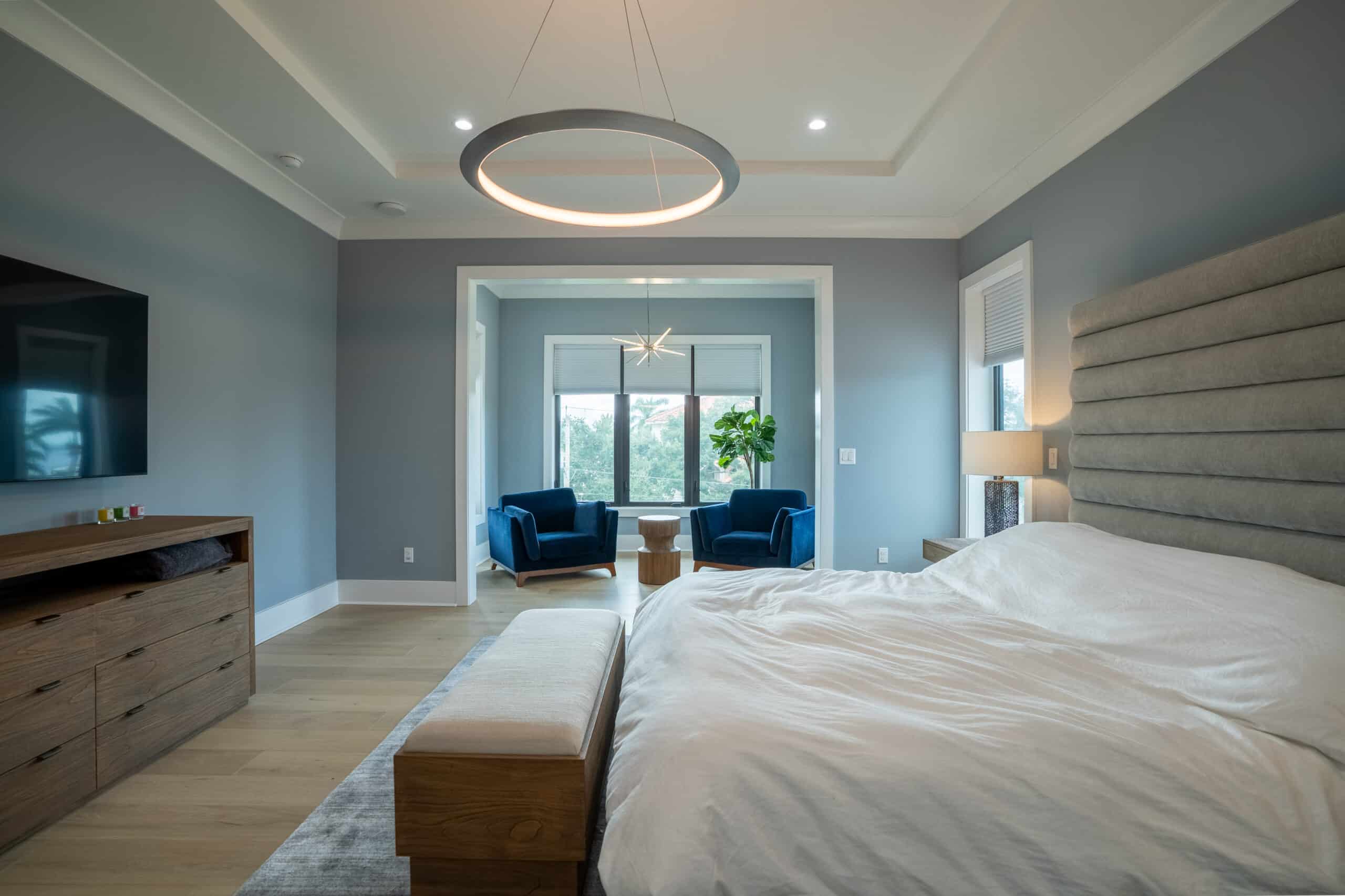Bedroom with an upholstered headboard wall and a sitting area by the window