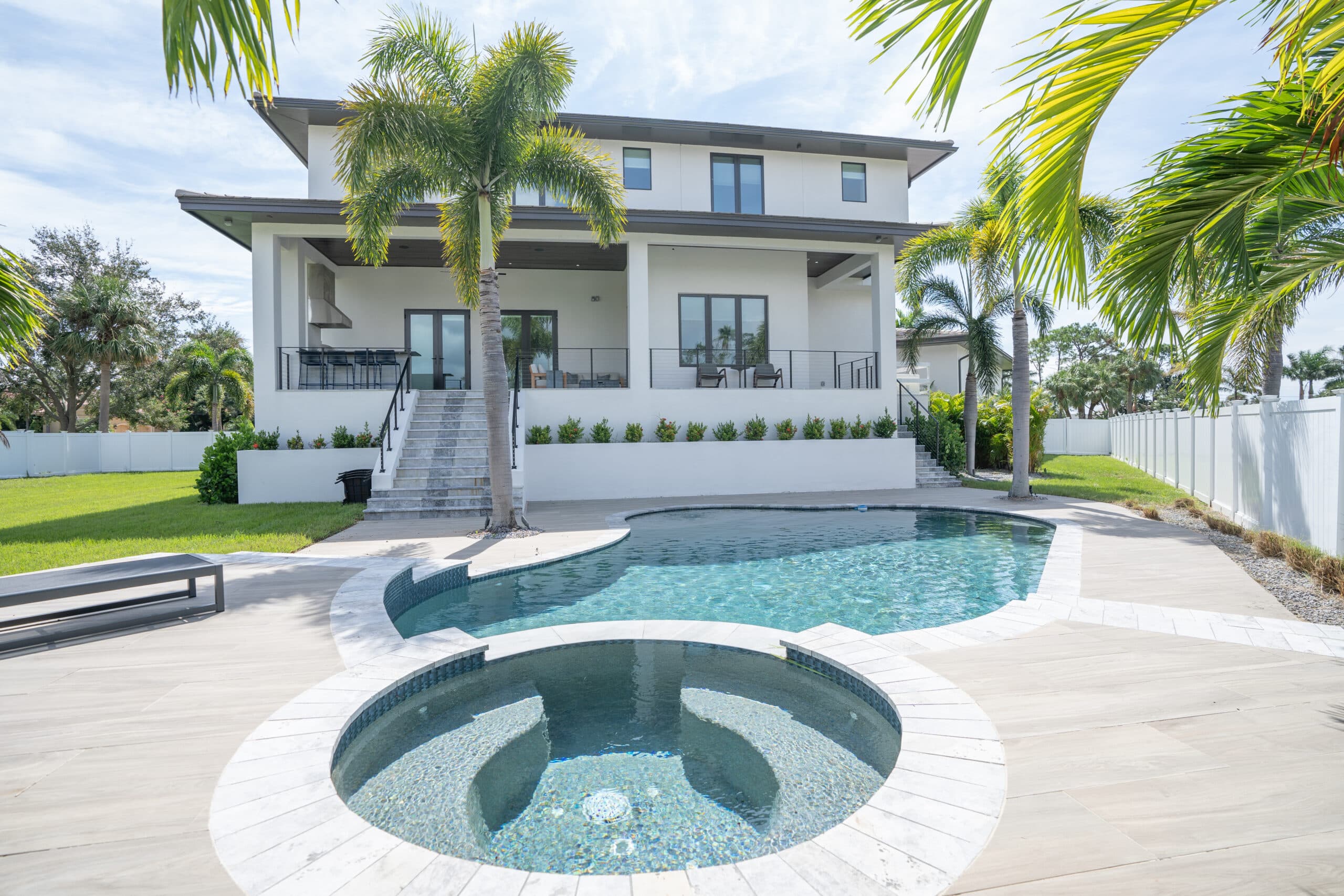 Back of the house with a pool and round spa in the foreground