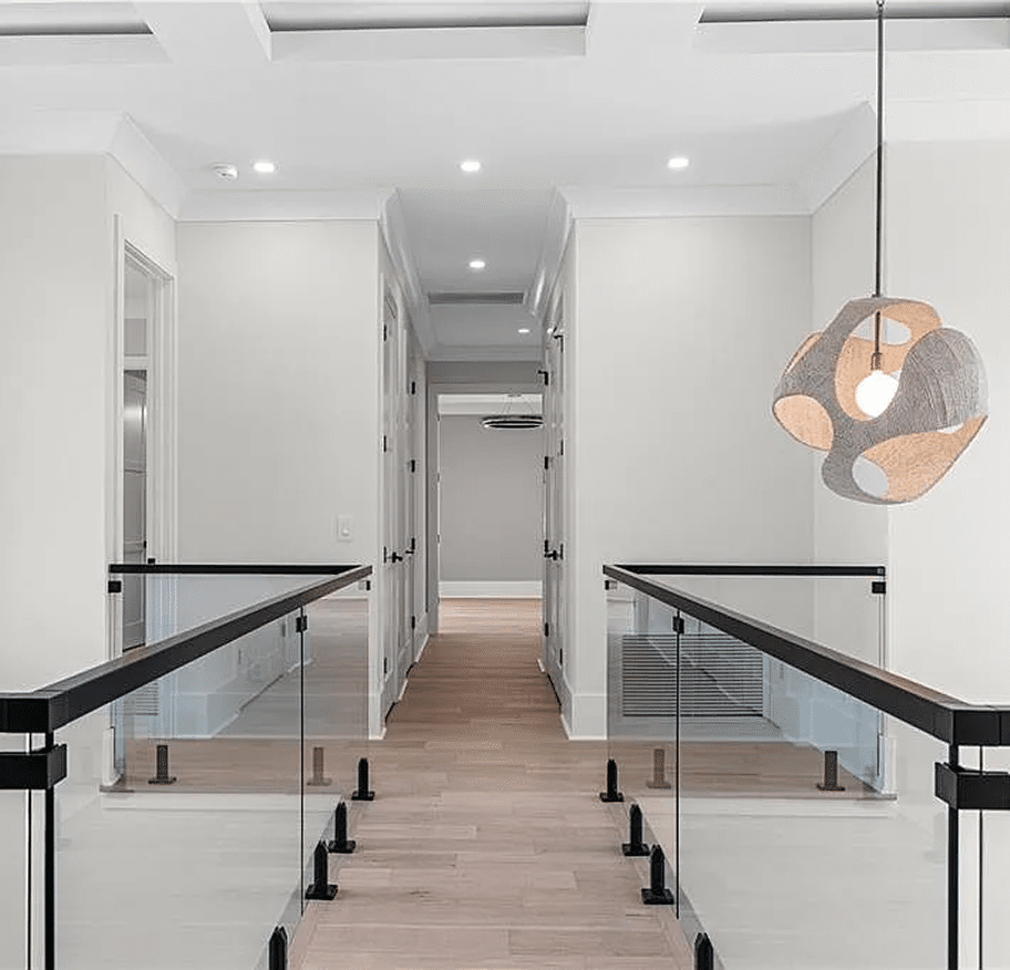 Upstairs landing with glass railings and a sculptural pendant