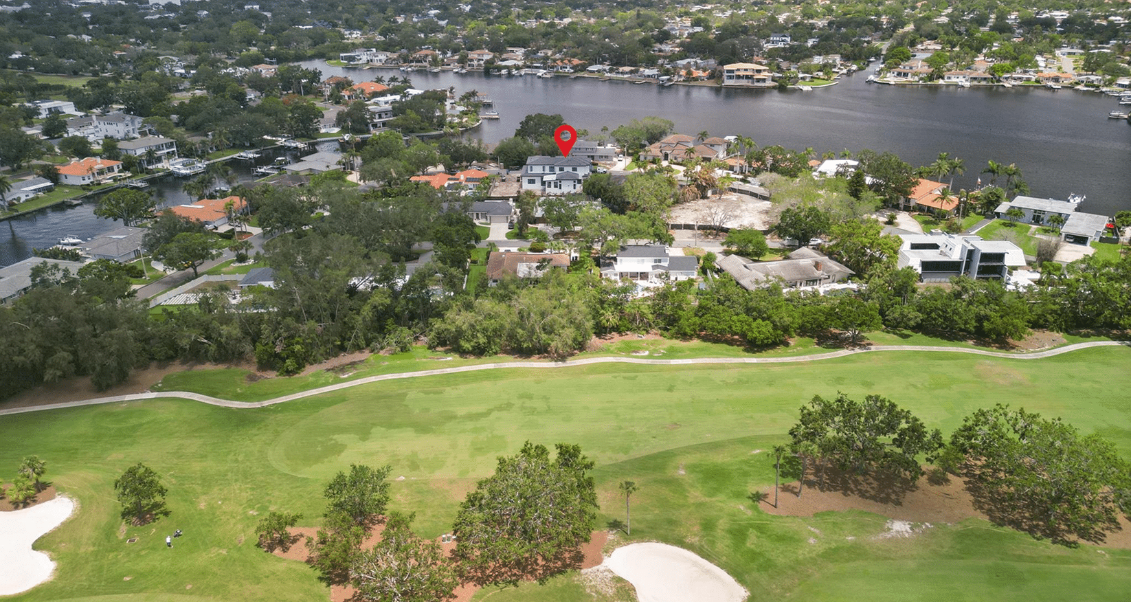 Aerial view with a location pin over a golf course neighborhood