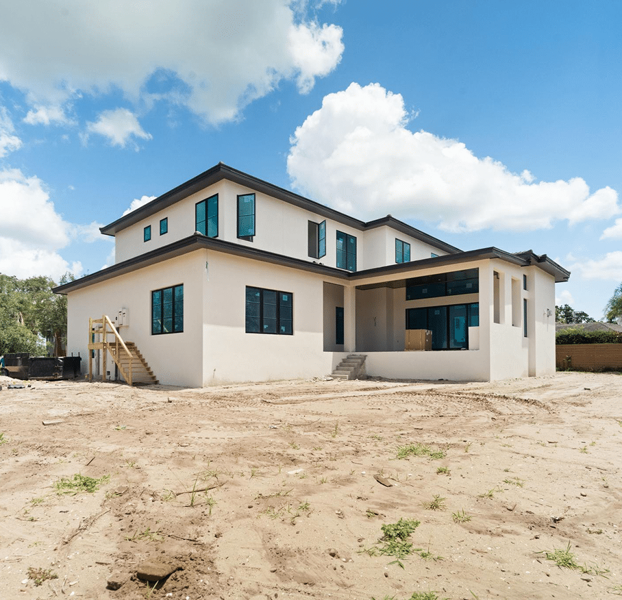 Home under construction with the stucco finished and the lot still bare