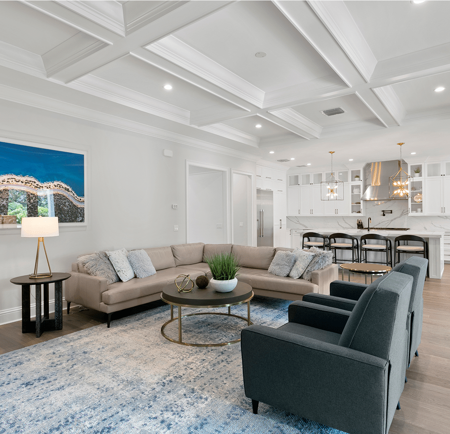 Living room with a coffered ceiling, sectional and the kitchen beyond